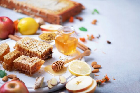 Autumn harvest concept. Set of honey and bee products, apple, lemon, spices on grey concrete
