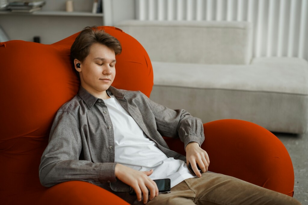 Calm young man enjoys listening chill music audio sound meditating feeling no stress at home