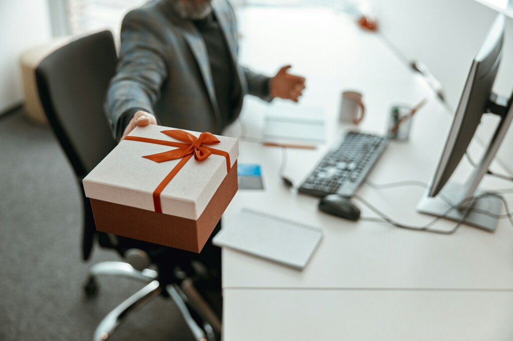 Cropped photo of gift box with red ribbon in male hands