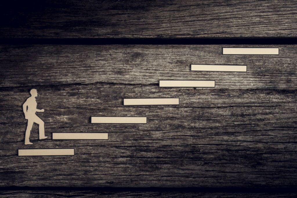 Cut outs of paper man climbing the steps to success