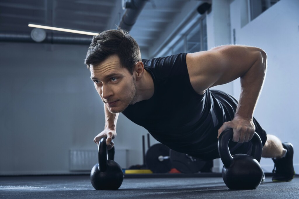 Man doing pushups on kettlebells at gym