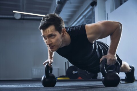 Man doing pushups on kettlebells at gym