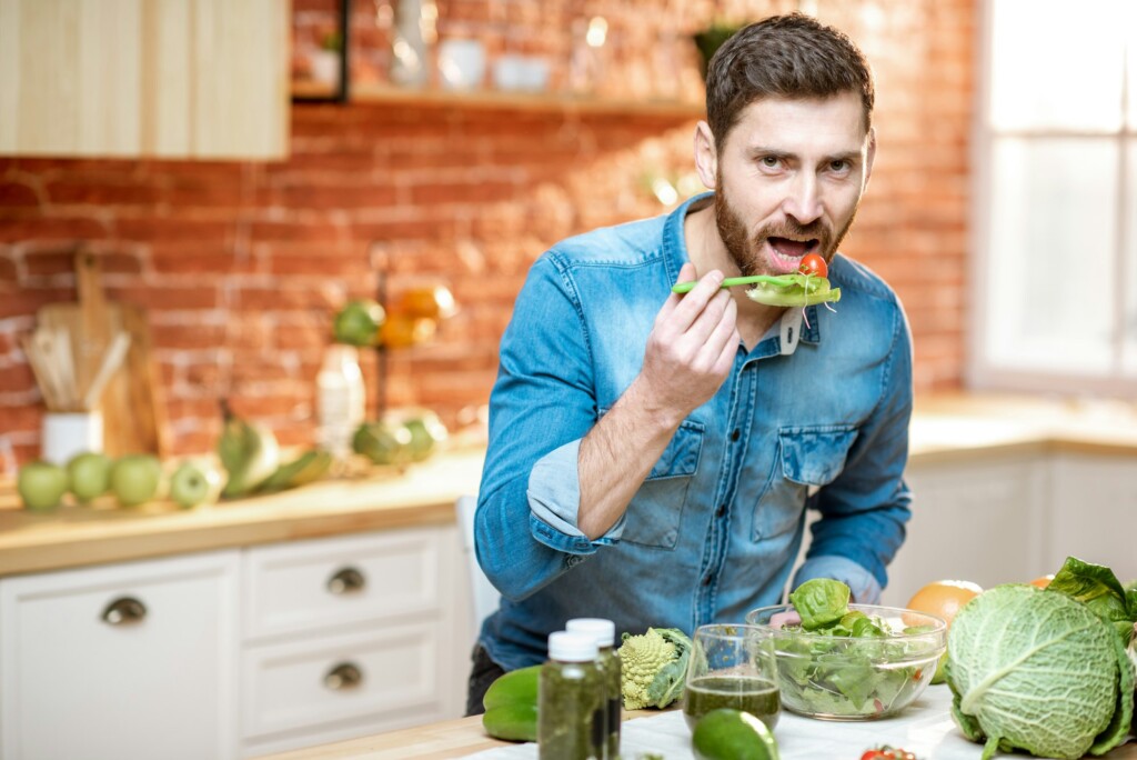 Man eating healthy salad on the kitchhen at home