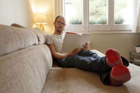 Man relaxing on sofa, reading book