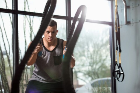 Man training with battle rope in gym