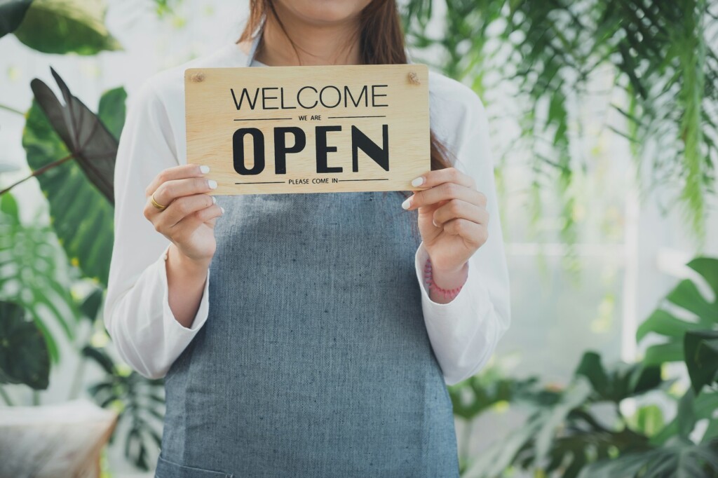 Portrait of cheerful owner standing at market stall.