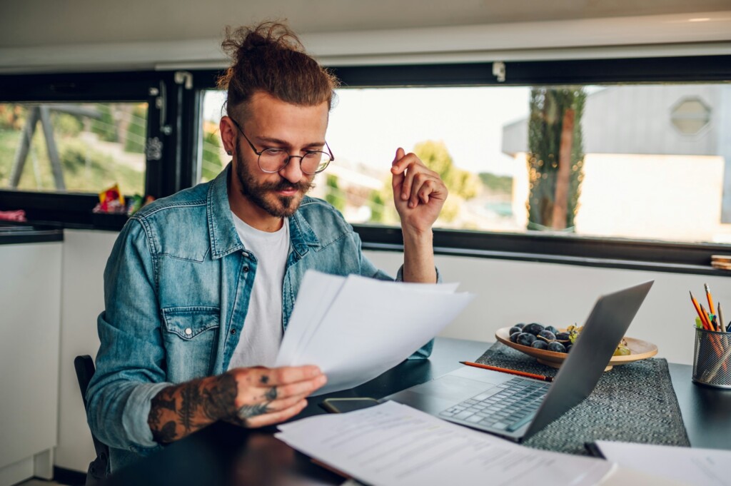 Young business man working at home with laptop and papers on desk